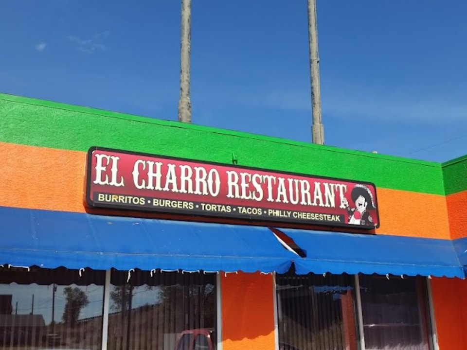 Street view of the El Charro sign listing burritos, burgers, tortas, tacos, and Philly cheesesteak, above a blue awning.